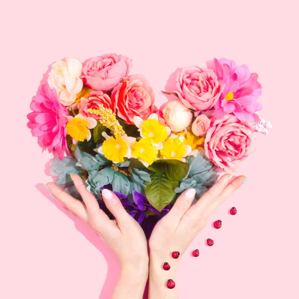 Person's hands holding a heart made of flowers